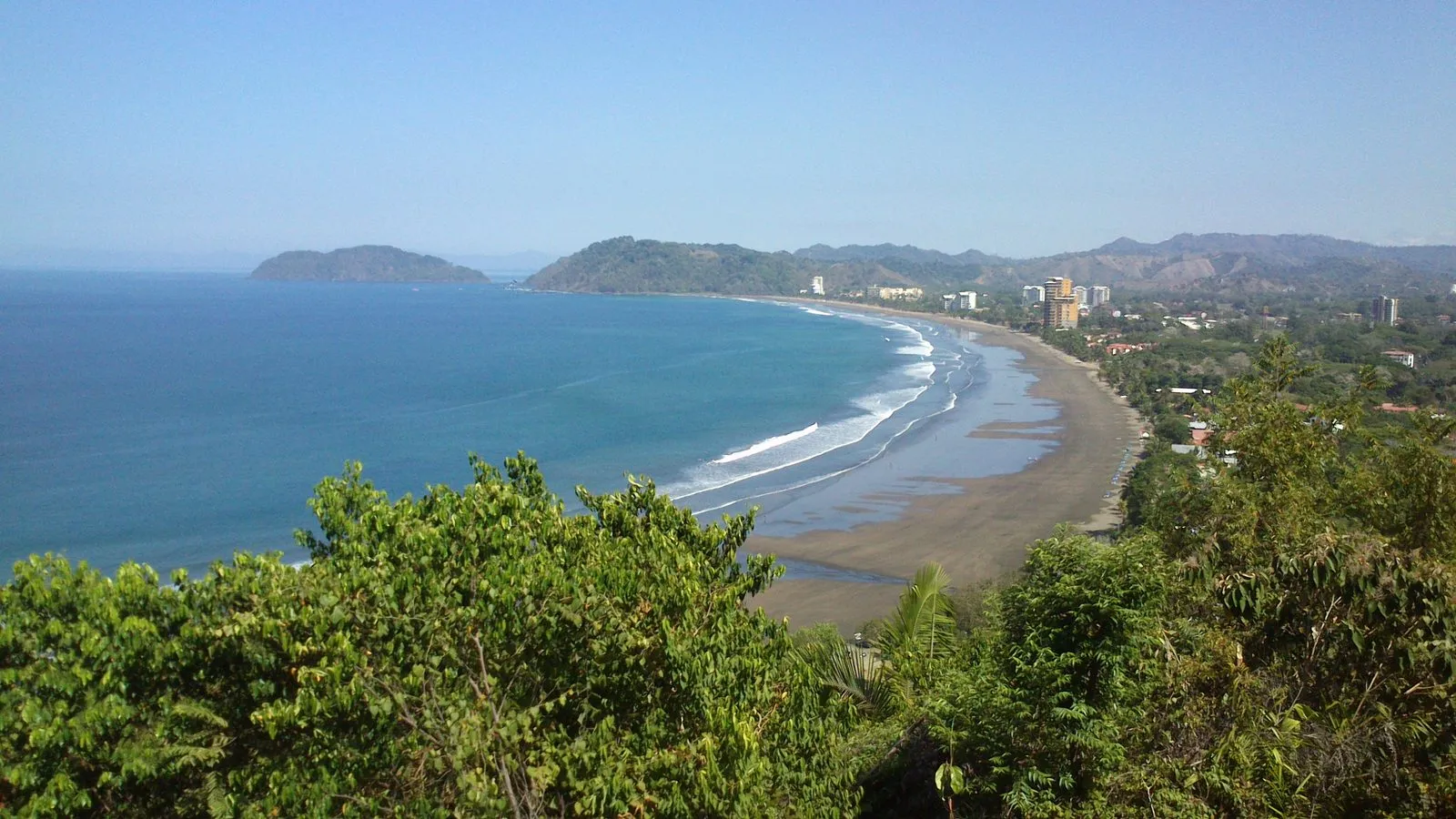 View over the long curve of Playa Jacó and the town from a hillside lookout.