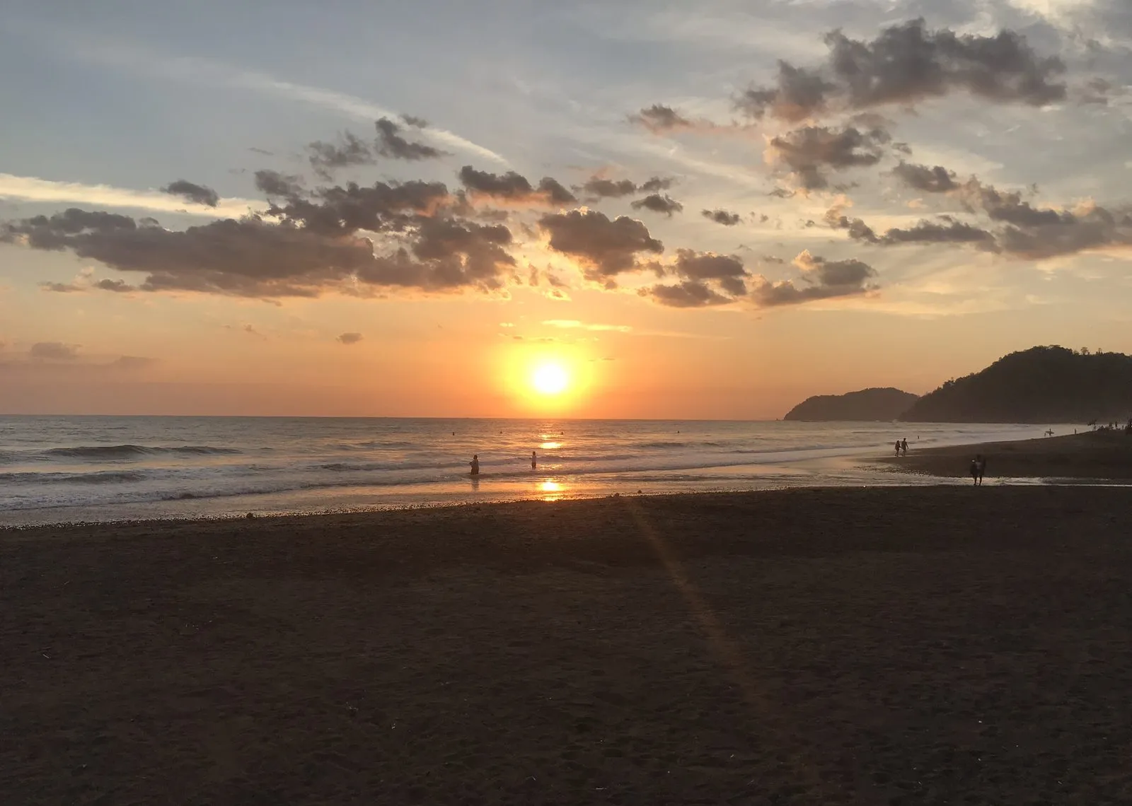 Pacific sunset over Jacó beach with the headland in the distance.