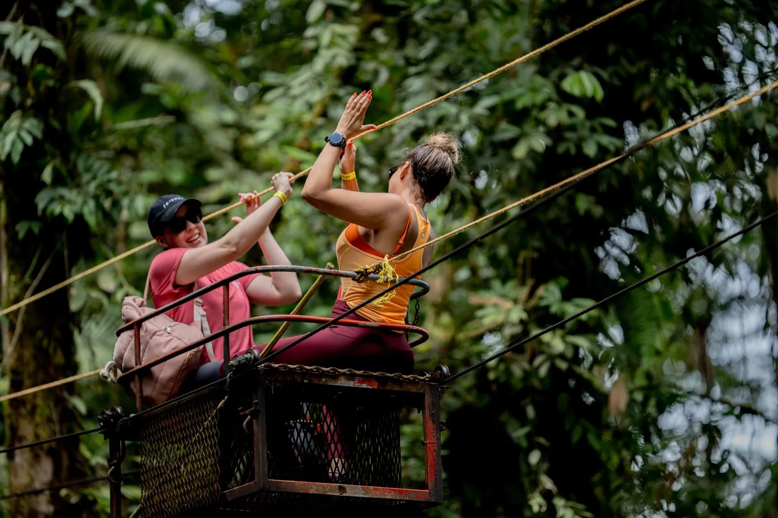 Two Amigo Turista guests high-fiving on a canopy tour in the rainforest