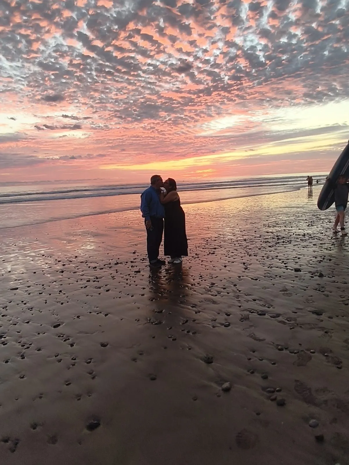 A couple silhouetted on the beach at sunset